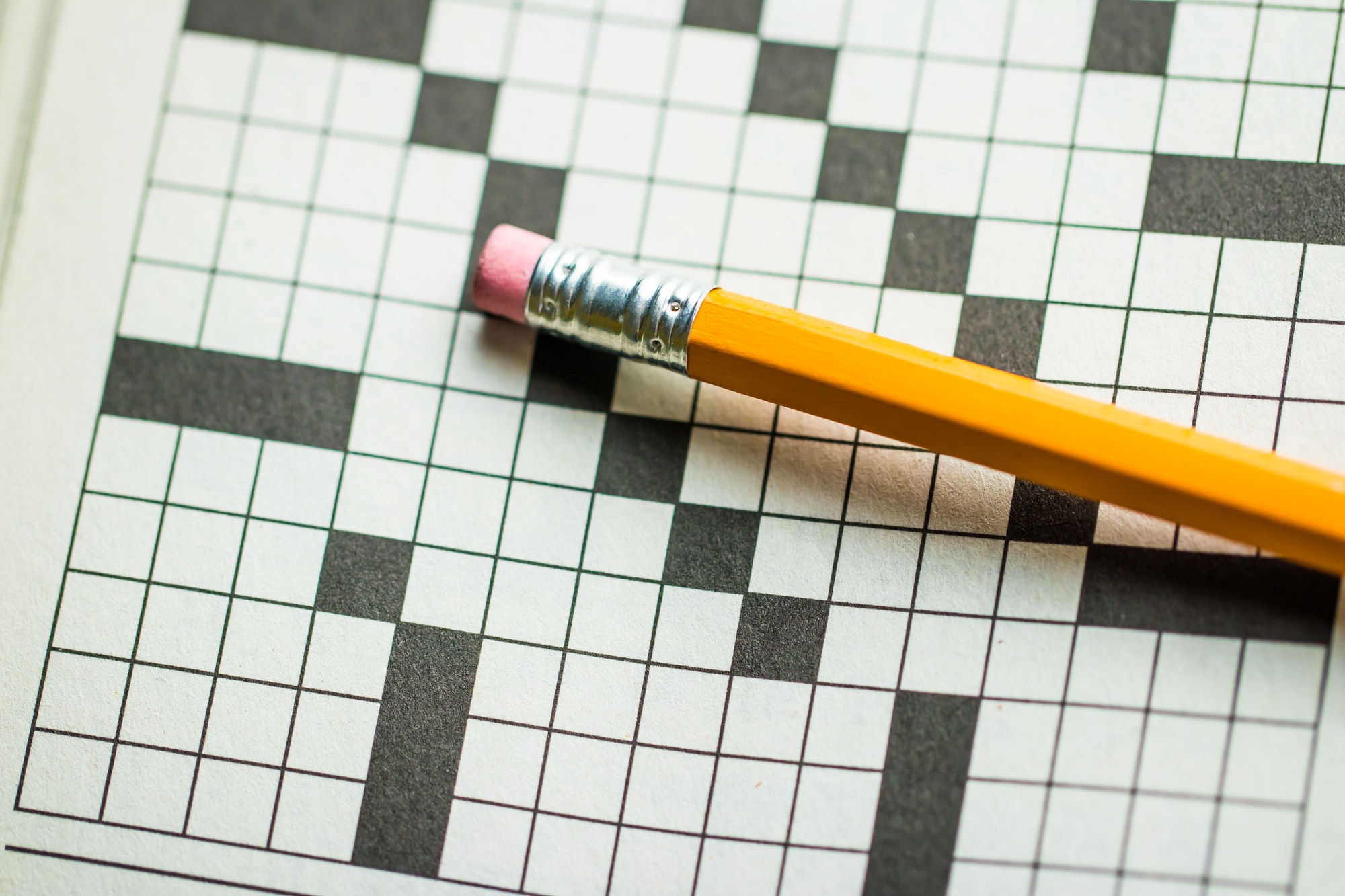 overhead angle of a pencil on top of a crossword puzzle