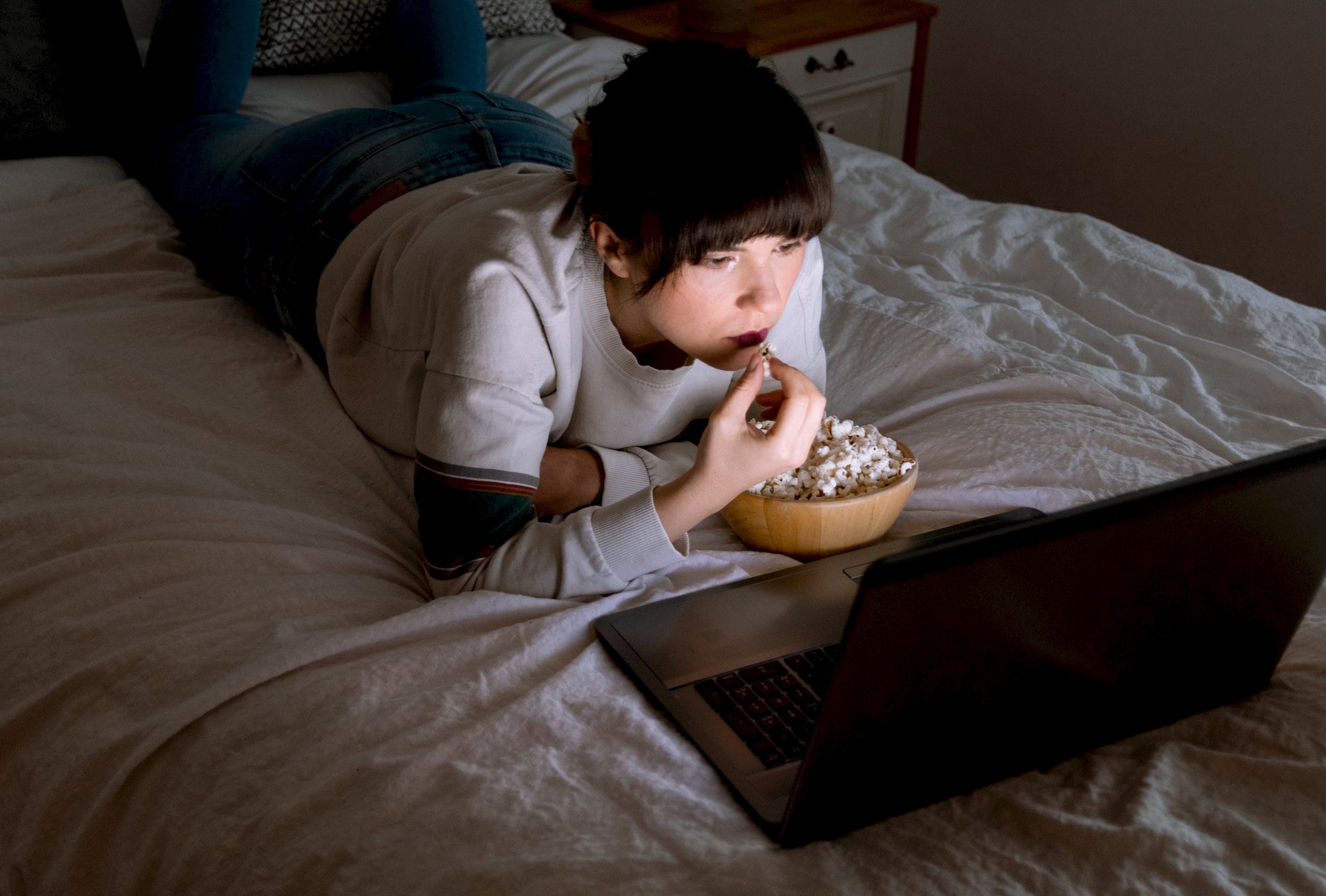 young woman watching movies on laptop in bed