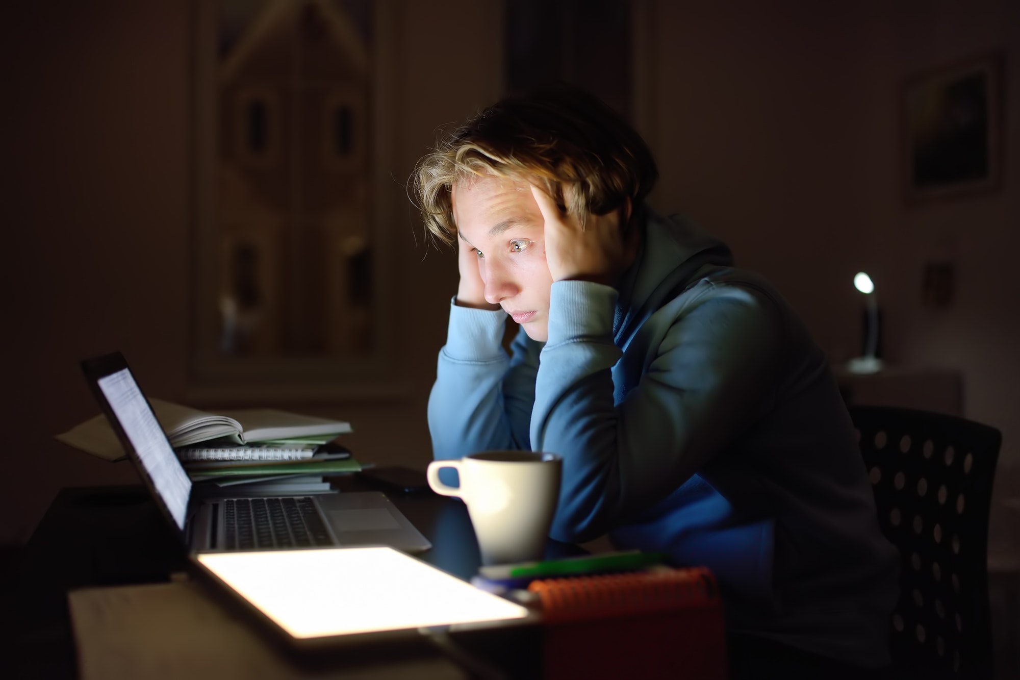 shocked teenger studying night at home with laptop and tablet pc