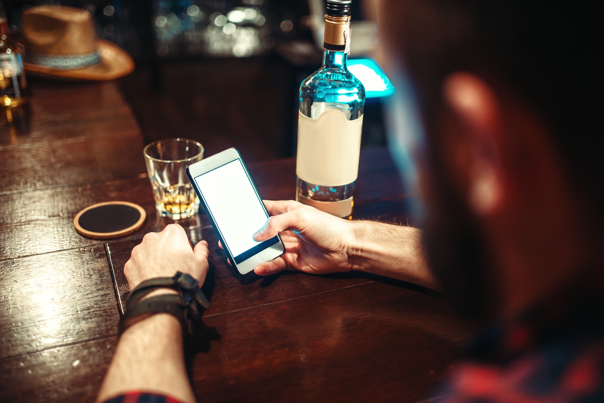 Male person with phone sitting at the bar counter