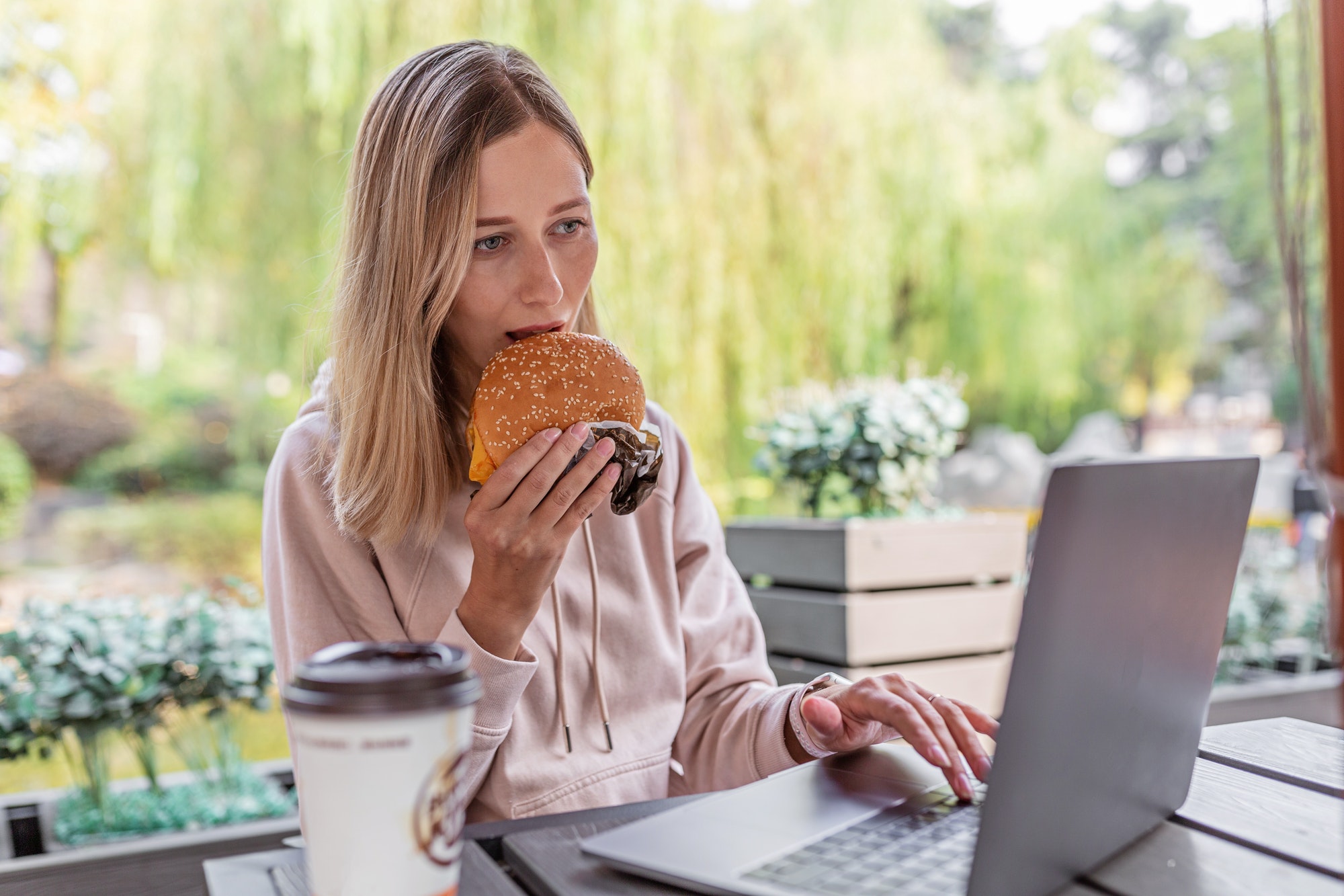 millennial business woman eating cheeseburger outdoor college life student using laptop technology
