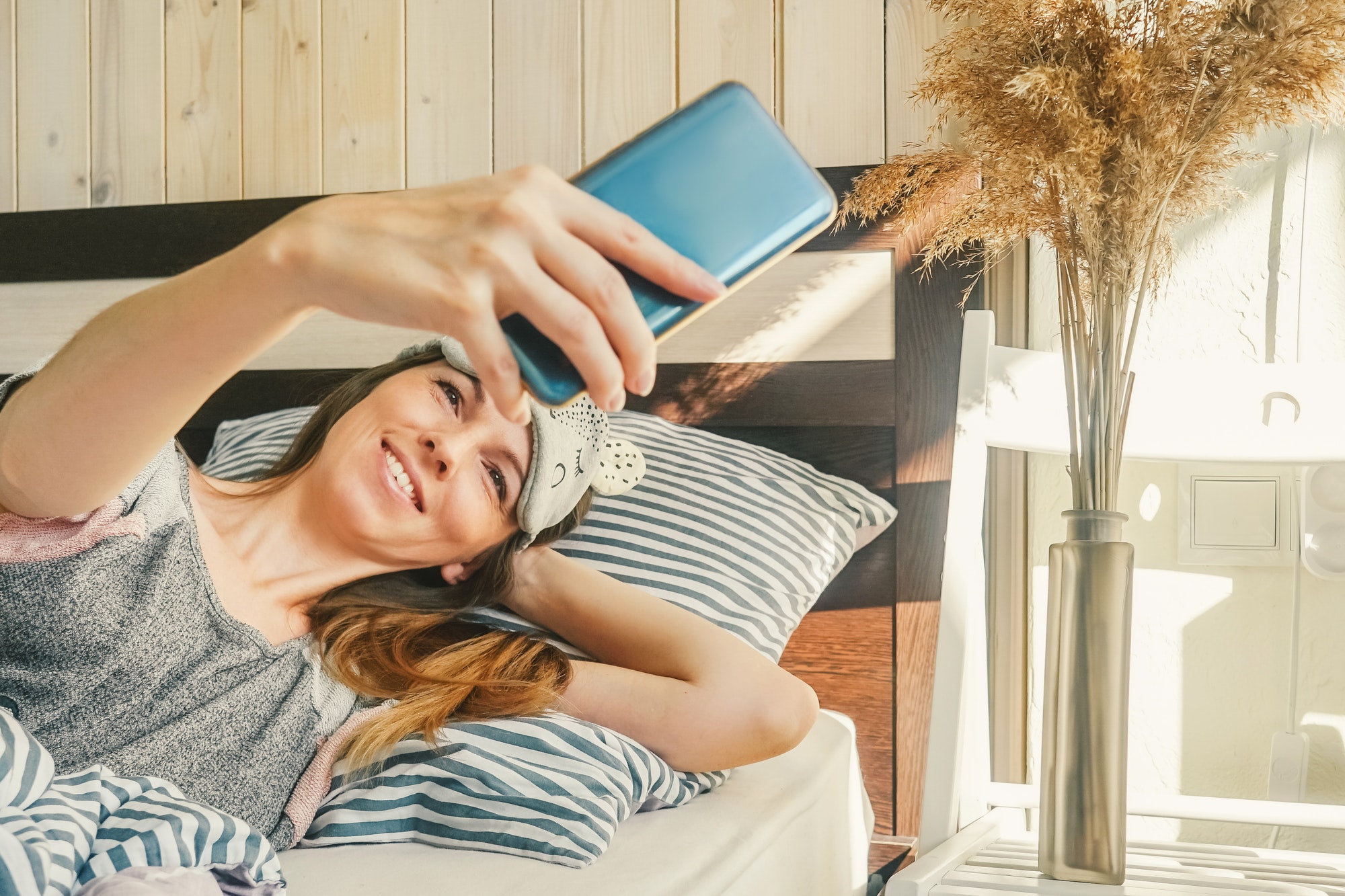 Woman with phone make selfie in bed.