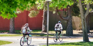 College students riding bicycles through campus on a sunny spring day