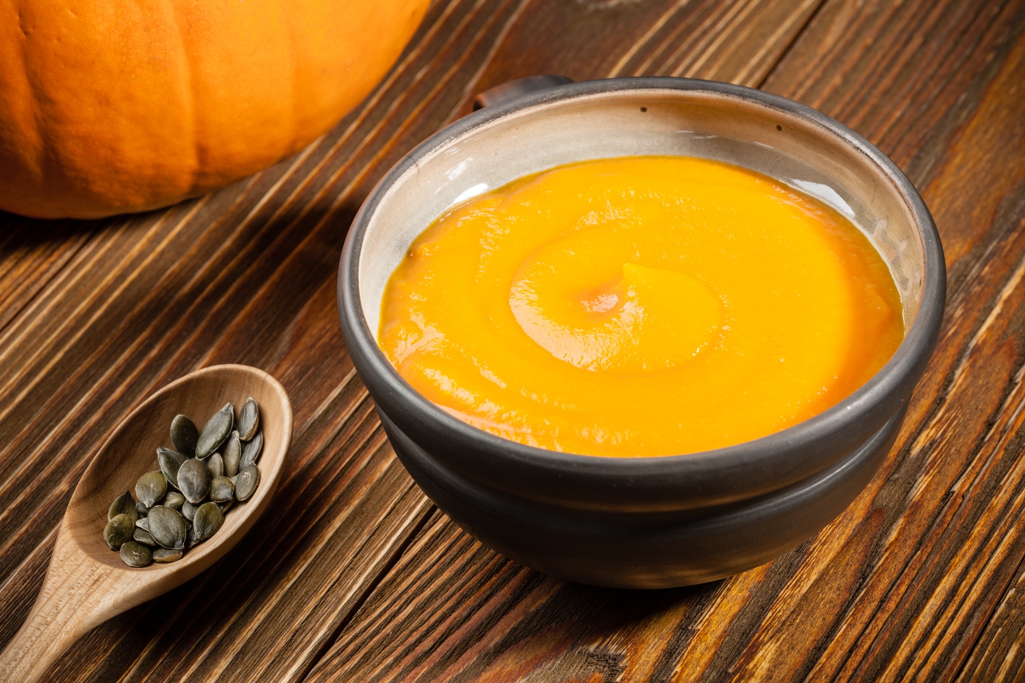 Pumpkin soup, pumpkin seeds on wooden table