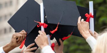 graduation hats and diplomas in students hands closeup