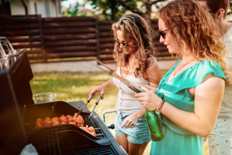 American girls having a backyard barbecue party with friends, laughing and smiling while cooking