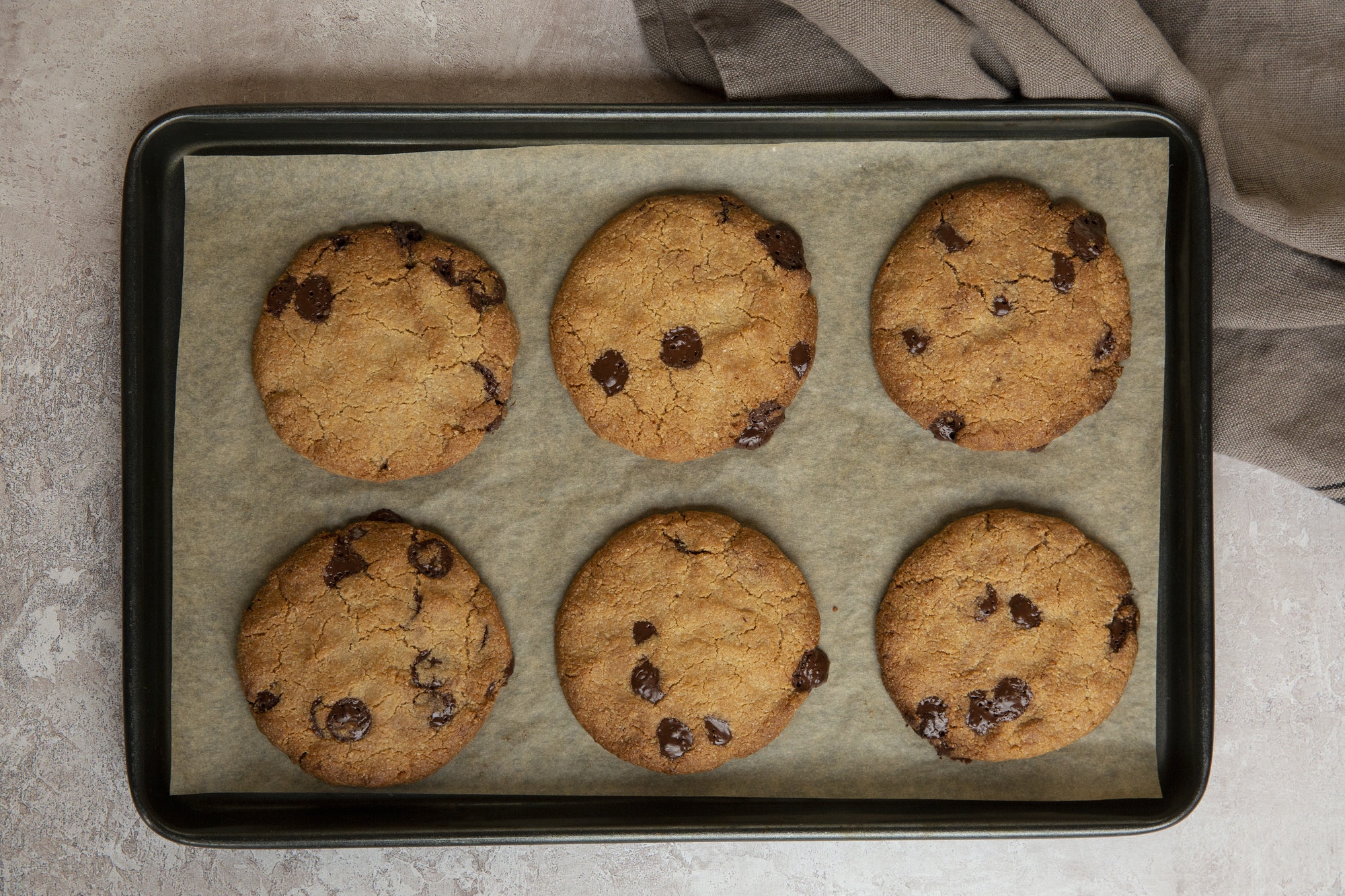 High angle close up of baking tray with freshly baked chocolate chip cookies.