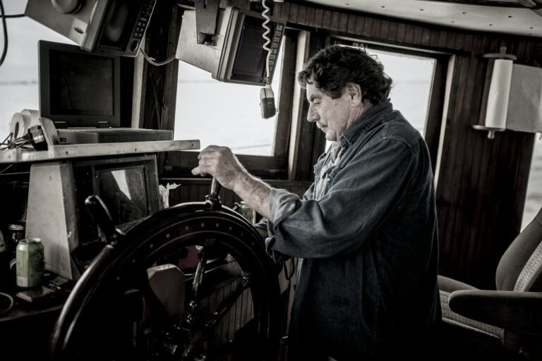 Ships captain at the wheel of a commercial fishing vessel.