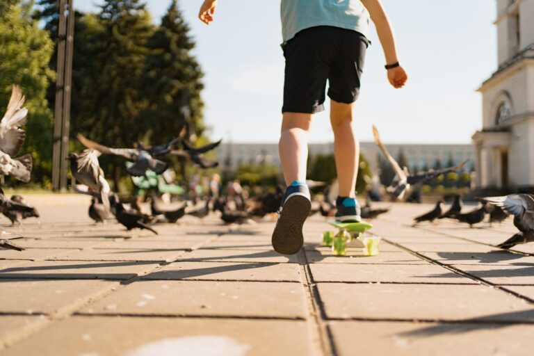 A boy riding a skate in the park with pigeons