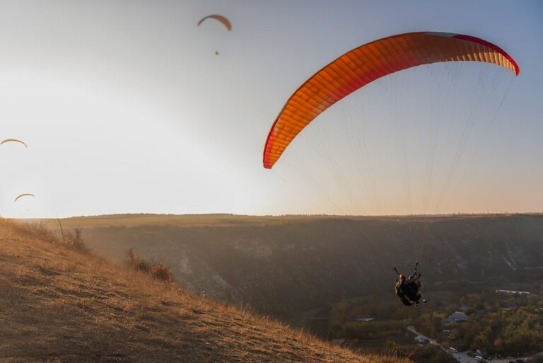 At sunrise in the blue sky paragliders fly in the rays of the golden sun