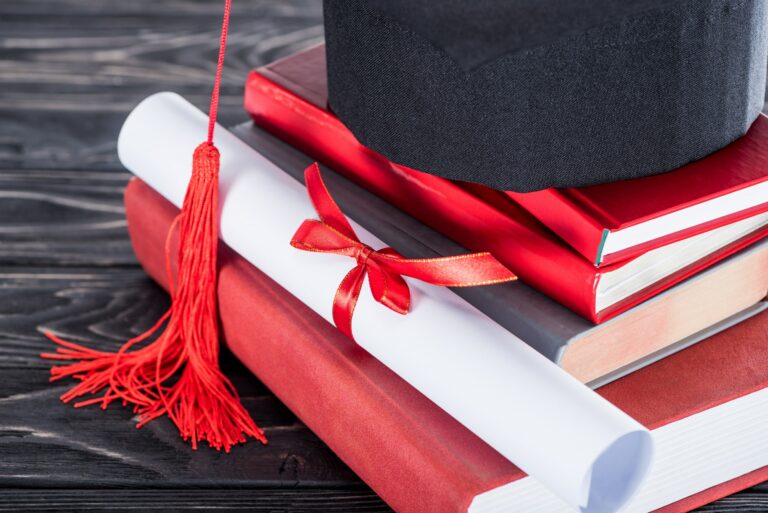 Graduation concept diploma and graduation cap on stack of books