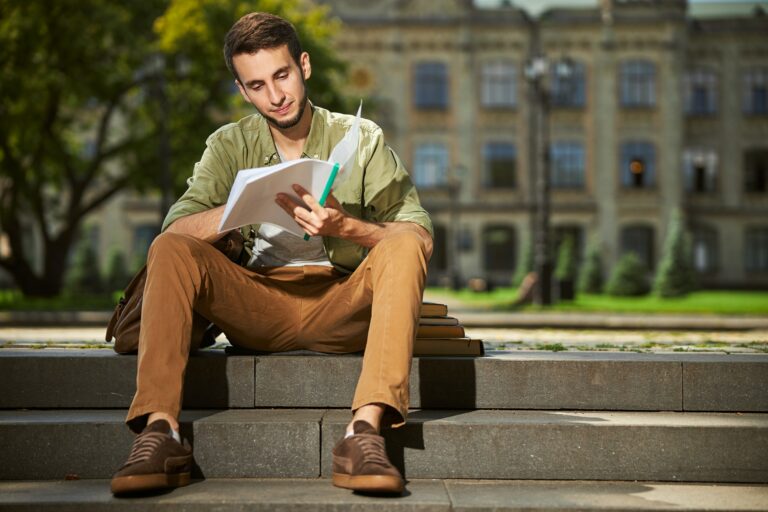 Focused university student doing his homework outside