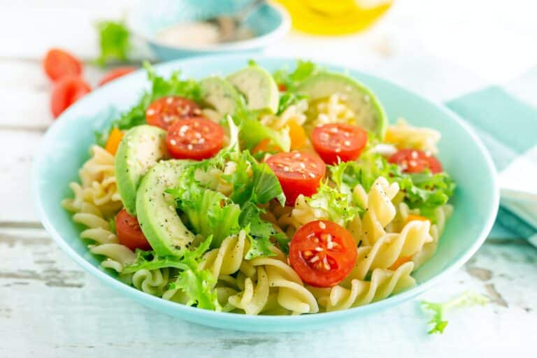 Pasta salad with avocado, fresh tomato, pepper and lettuce, top view