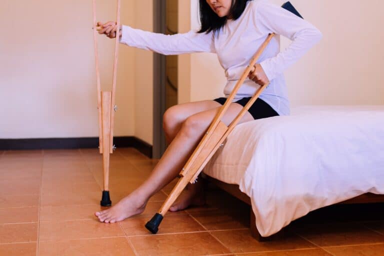 Woman patient using crutches and broken leg for walking in bedroom,Close up