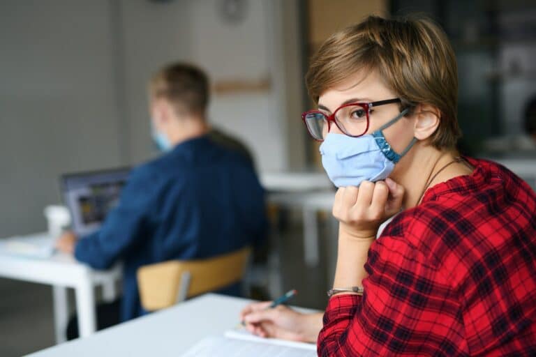 Young student with face mask at desk at college or university, coronavirus concept.