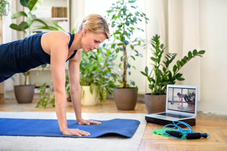 Woman indoors doing fitness workout at home, watching online video tutorial