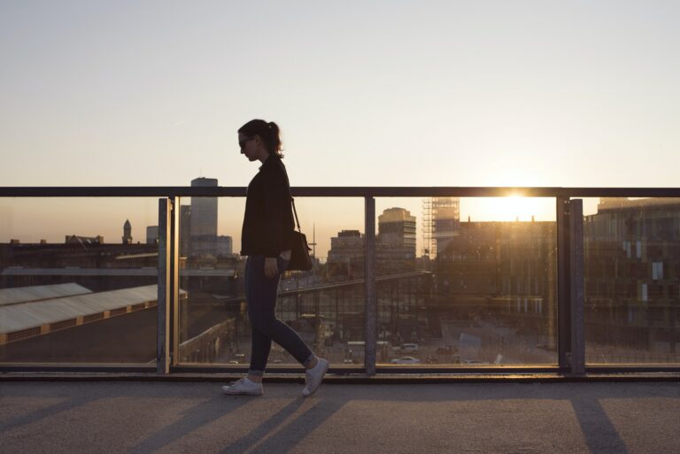 Woman walking on elevated walkway at sunset