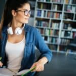 Beautiful happy student woman studying in library
