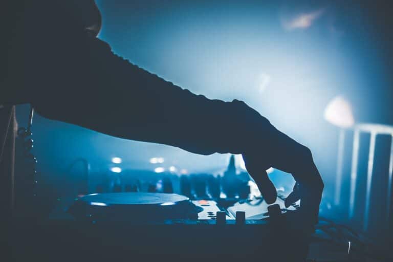 DJ changing the song at a night club. Close up of silhouetted hand