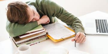 Student at the table indoors sleeping on books.