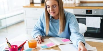 Image of focused woman smiling while studying with exercise books