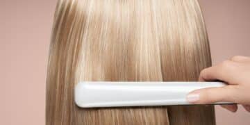 Hairdresser straightening long hair with hair irons