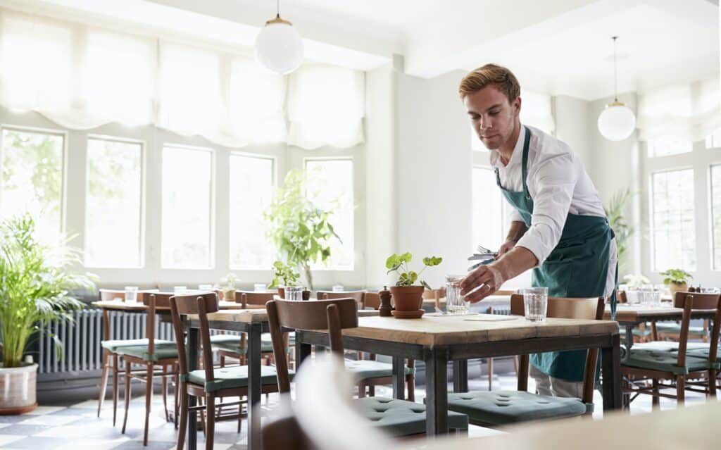 waiter laying tables in empty restaurant