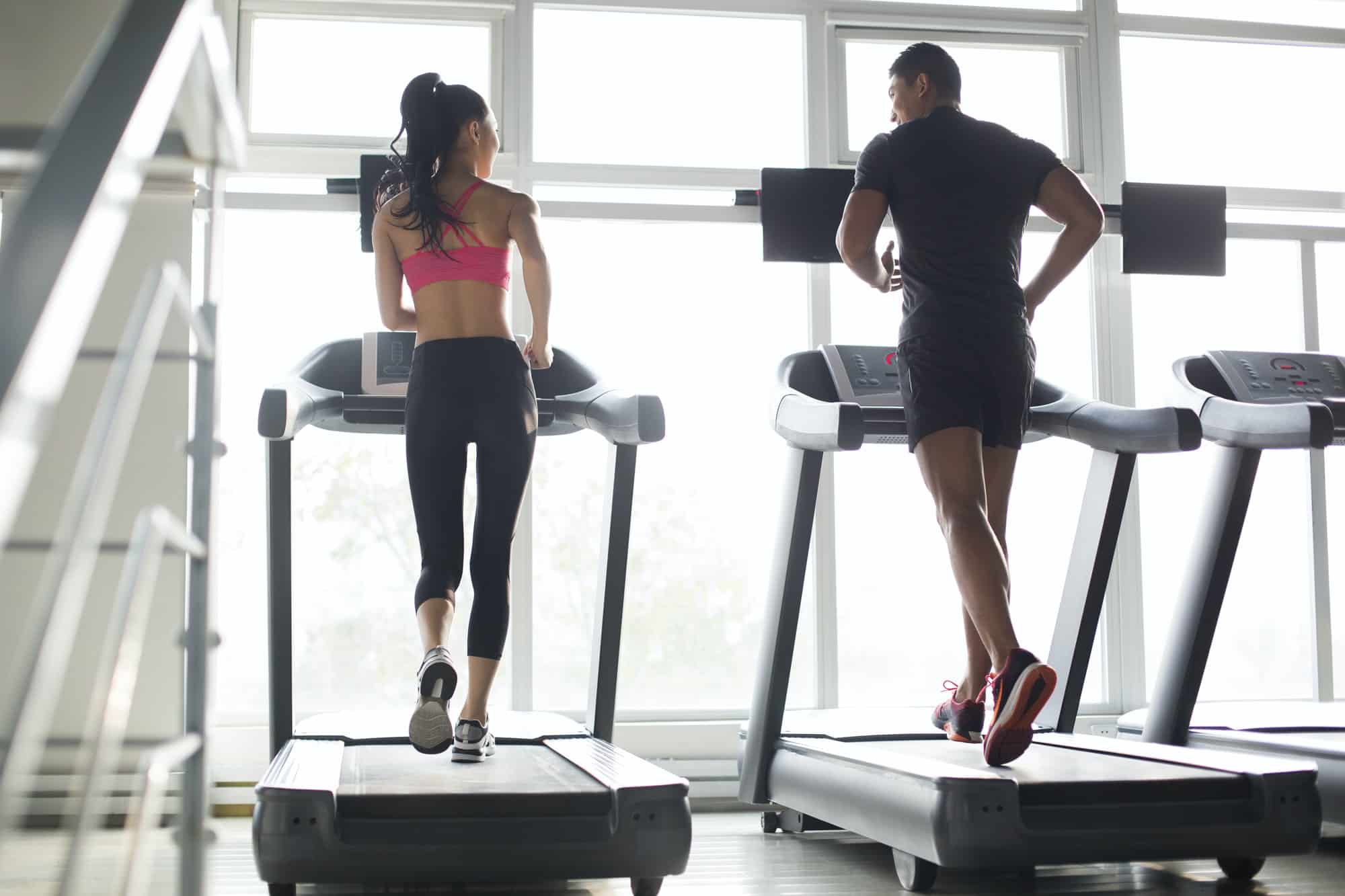 young couple exercising on treadmills in gym