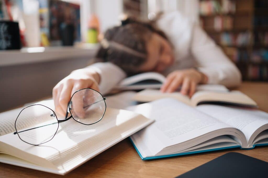 Student girl felt asleep studying among many books