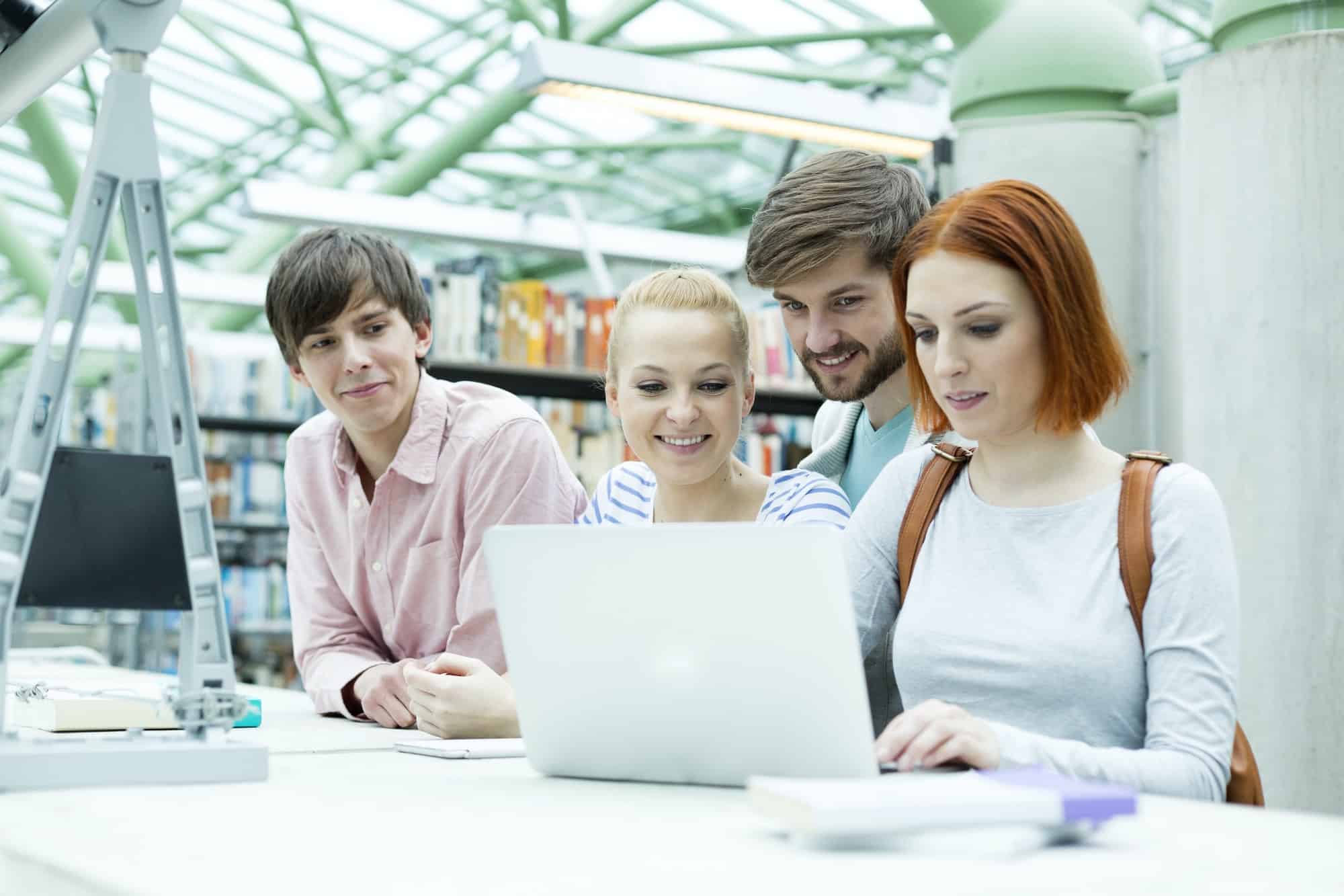 students in a university library using laptop