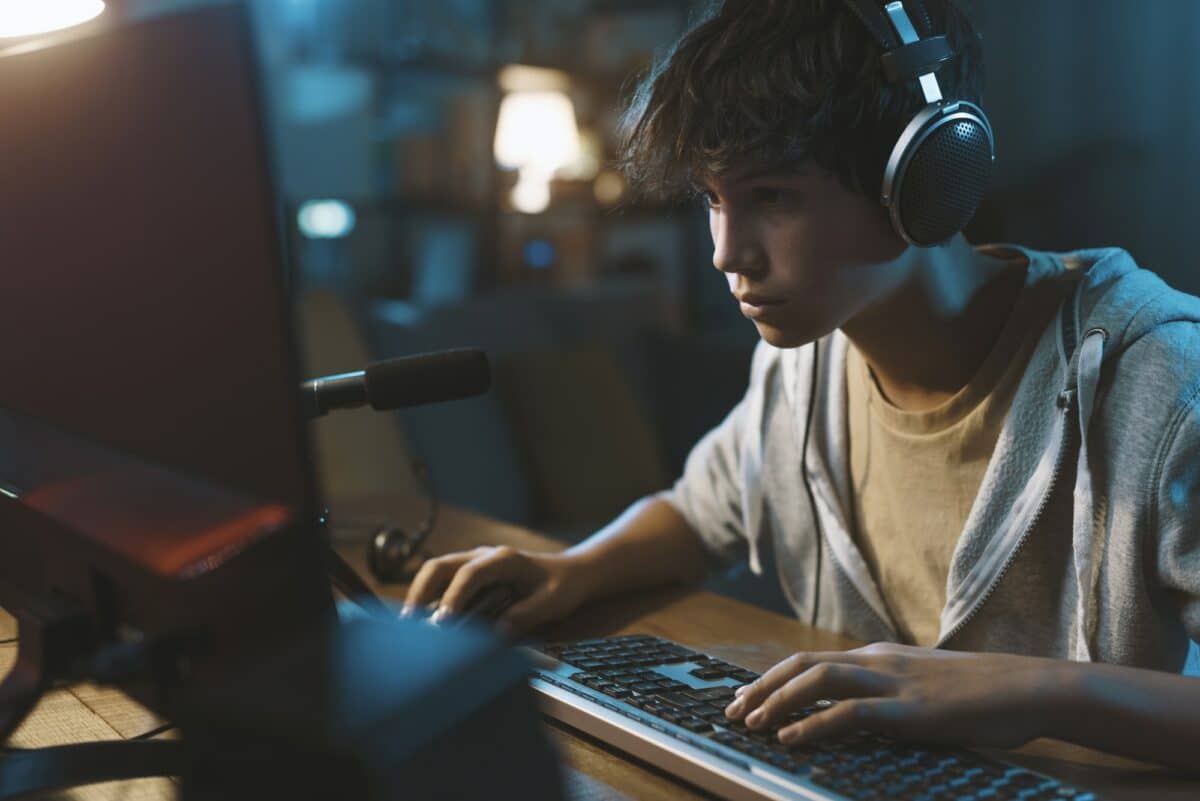 teenager wearing headphones and playing online video games e1658608420762