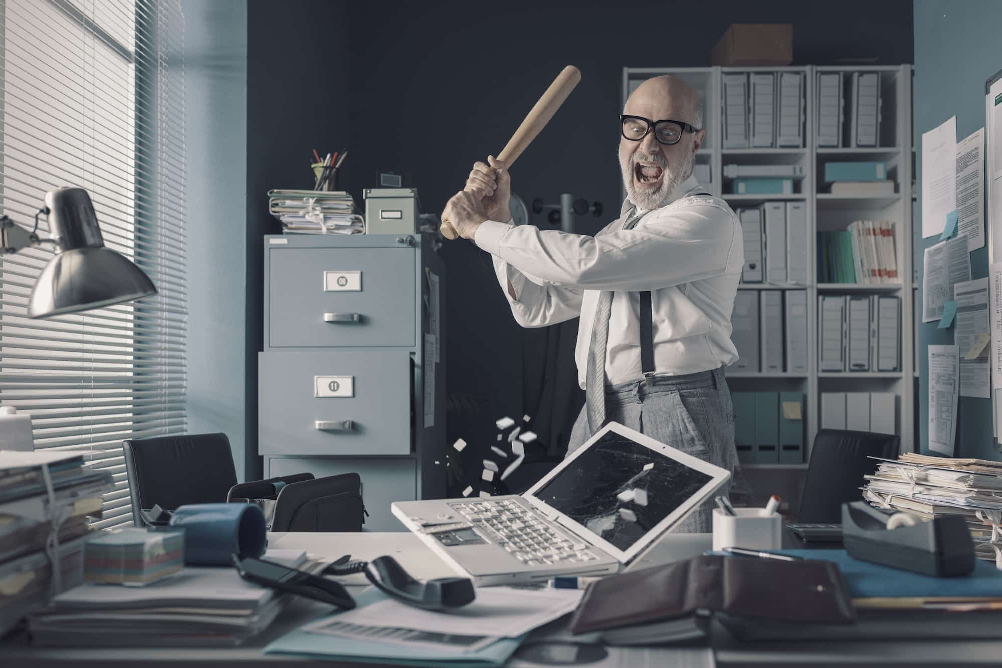 crazy businessman destryoing his office with a baseball bat