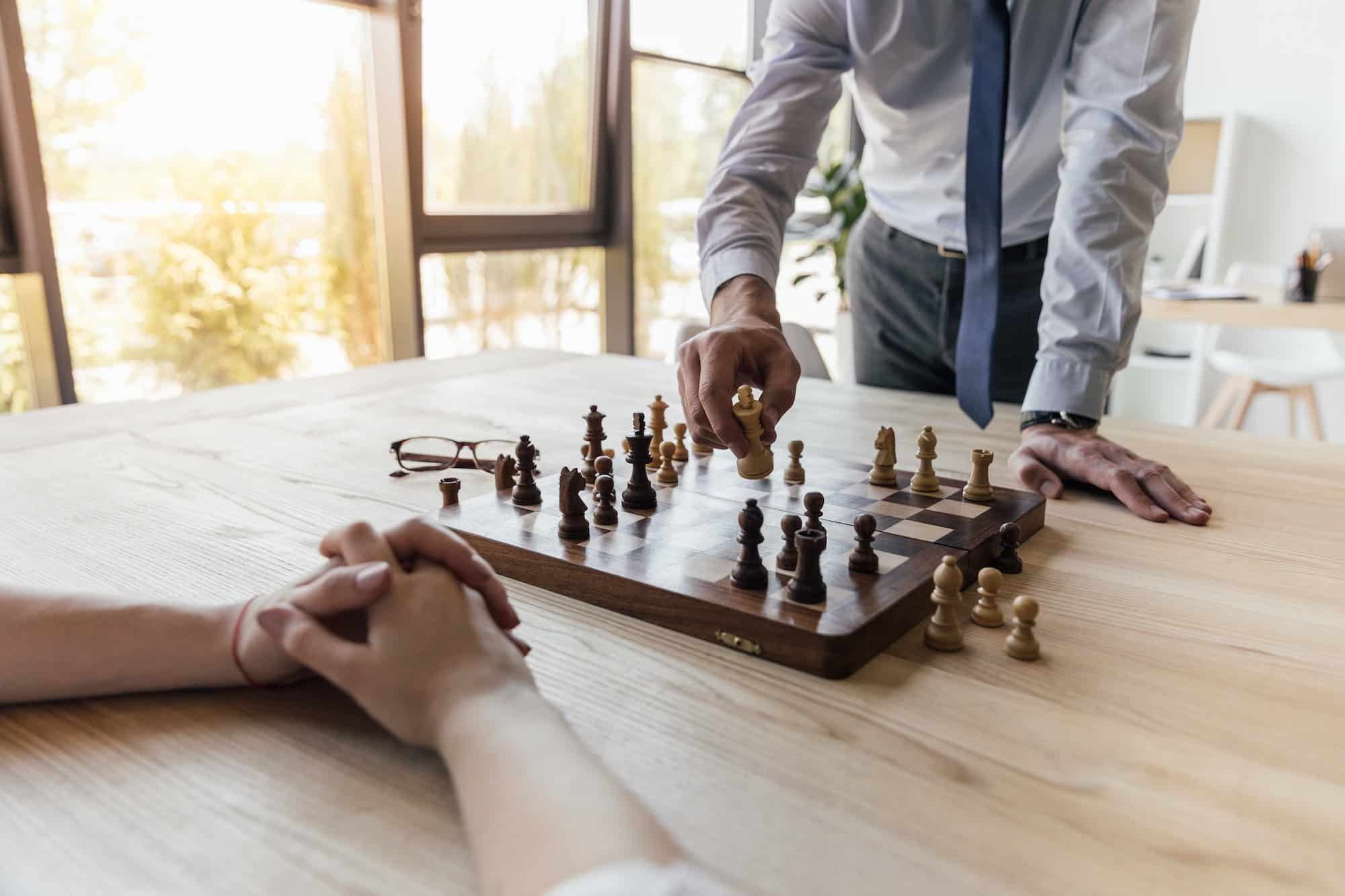 partial view of businessman playing chess with colleague in office