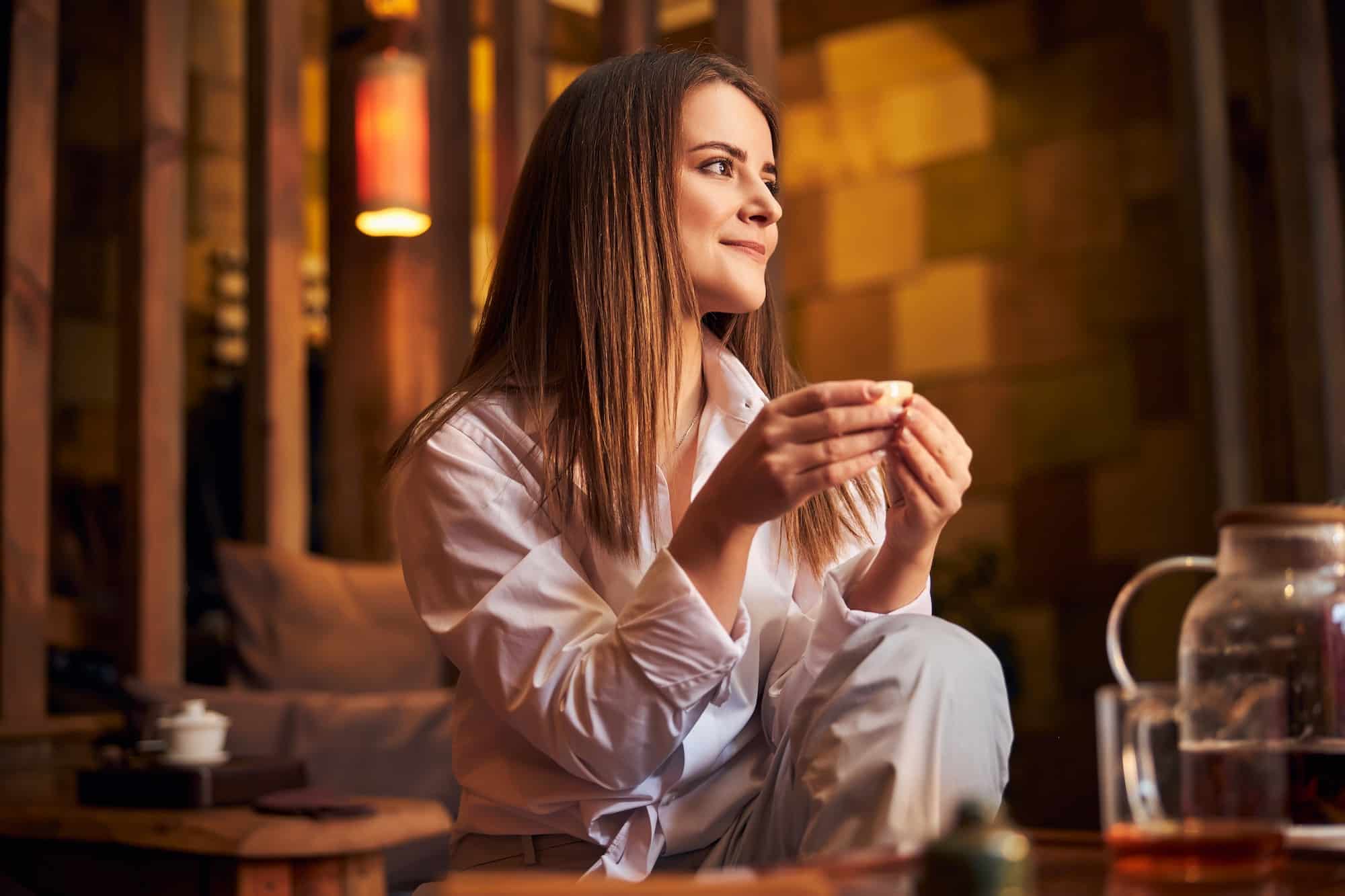 charming young woman drinking tea in cafe