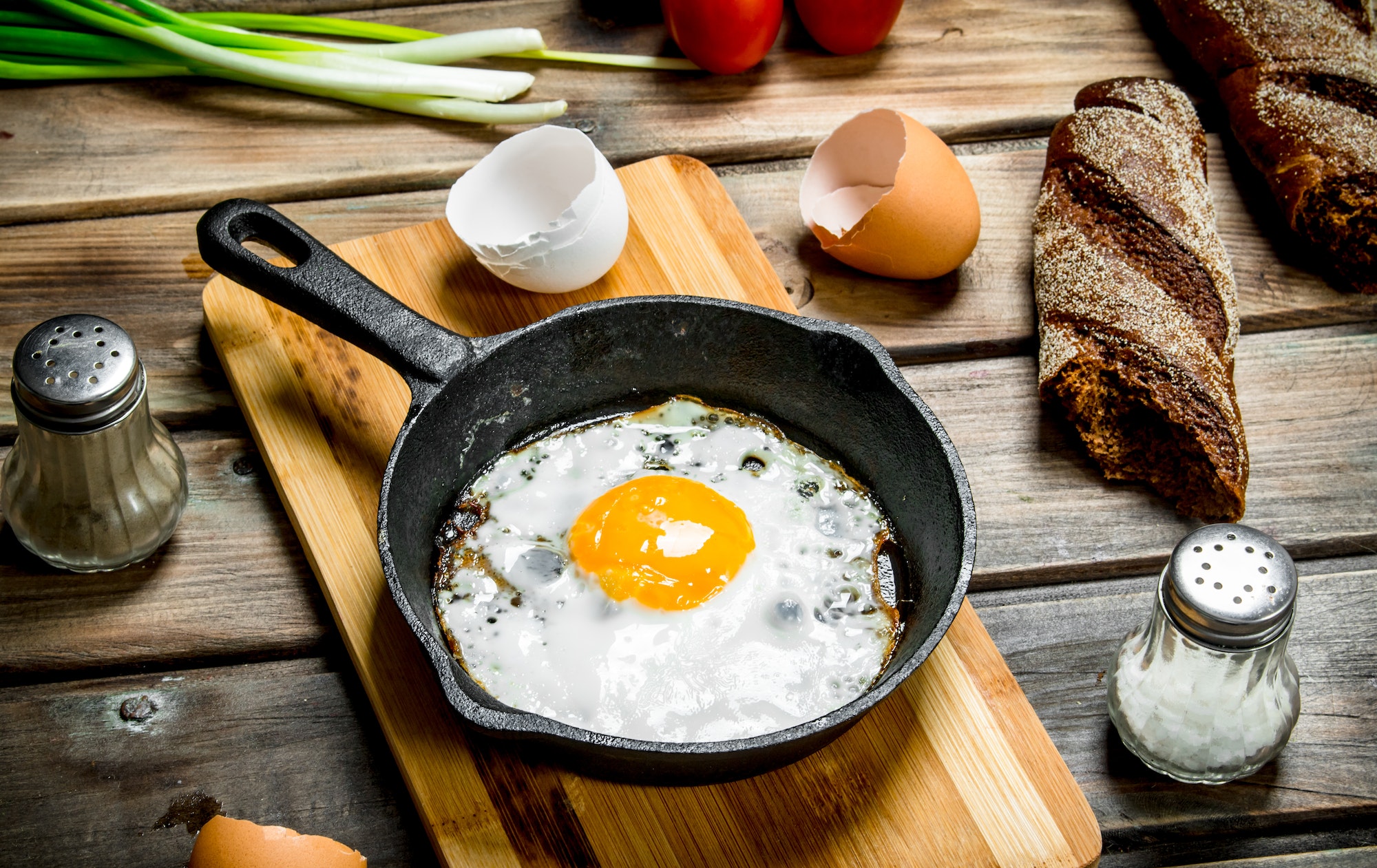 fried egg in a pan with bread tomatoes and green onions