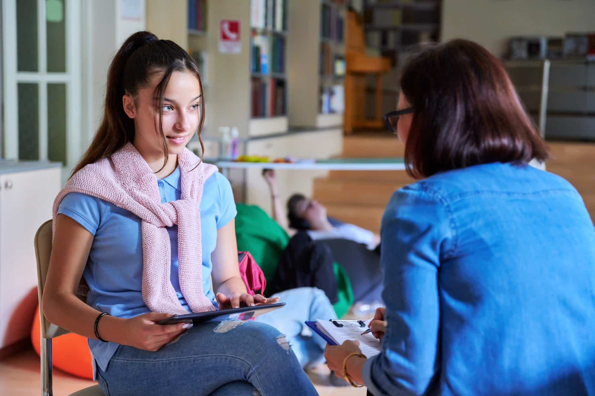 woman school psychologist teacher talking and helping student girl teenager
