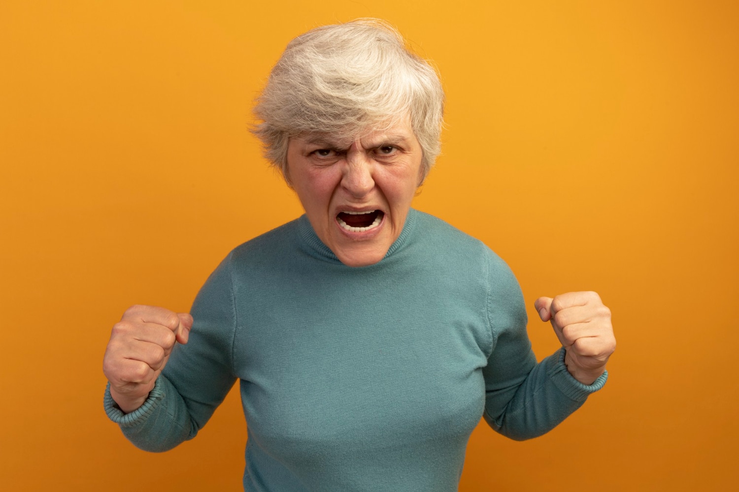 angry old woman wearing blue turtleneck sweater clenching fists screaming