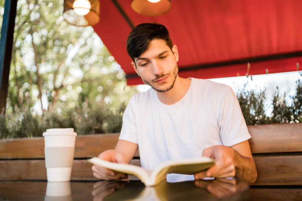 portrait caucasian man enjoying free time reading book while sitting outdoors coffee shop lifestyle concept