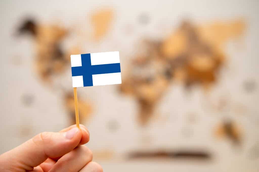 Finland flag in mans hand on the world map background.