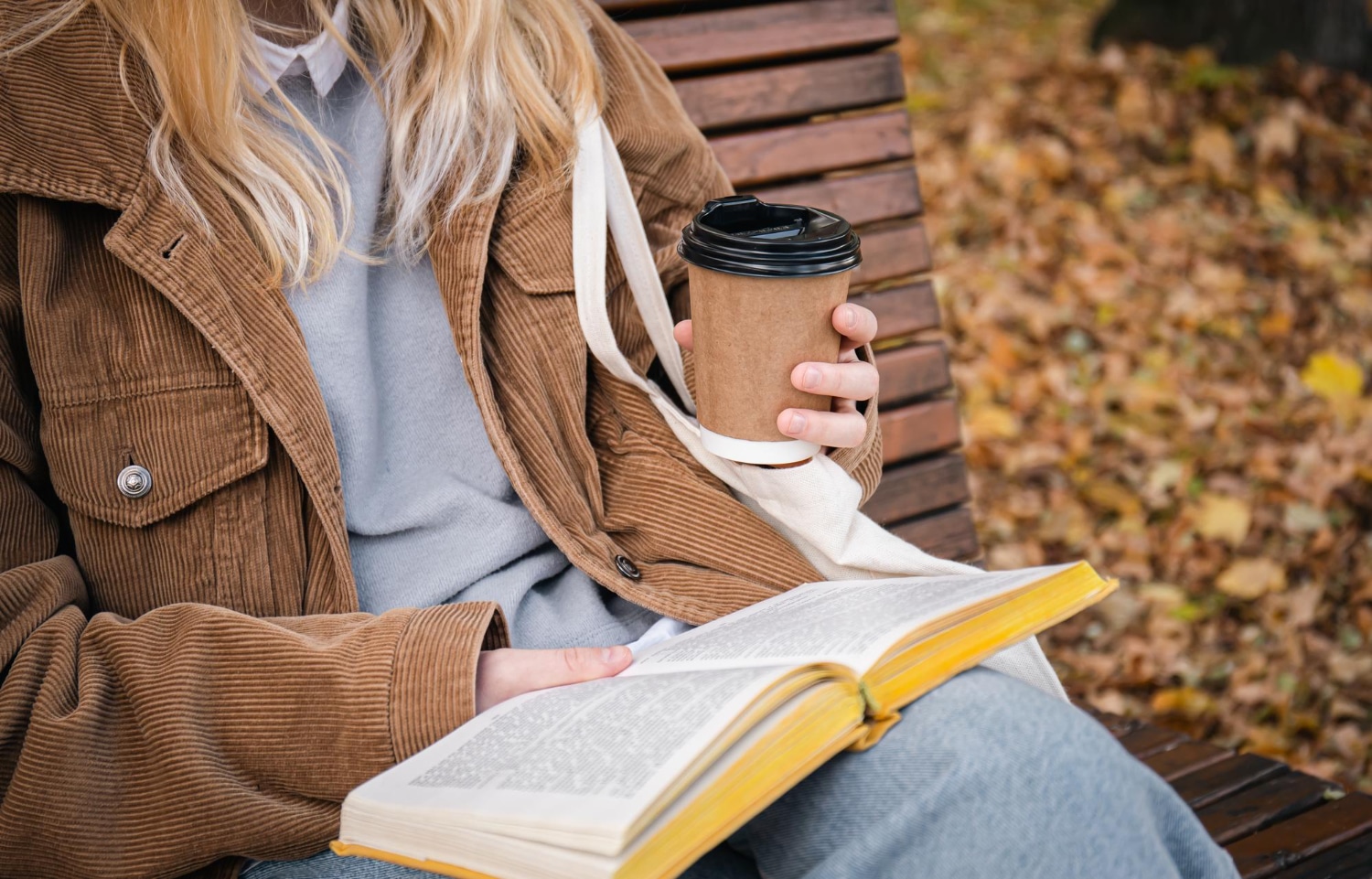 young woman sits bench autumn park drinks coffee reads book