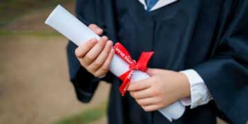 Kids on graduation gown holding graduation scroll