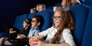 Kids watching movie in cinema, holding popcorn buckets