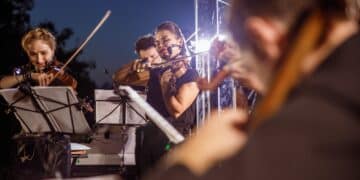 Violin players playing in orchestra at night outdoor concert